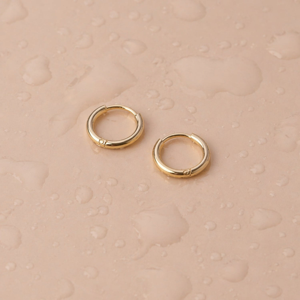 Tiny 14k Gold Huggie Hoop Earrings Flat Lay, Small Waterproof Tarnish-Resistant Hoops